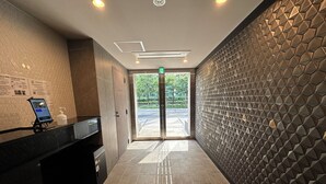 Una zona de recepción moderna con un quiosco digital, una señal de salida visible y un diseño de pared geométrico.