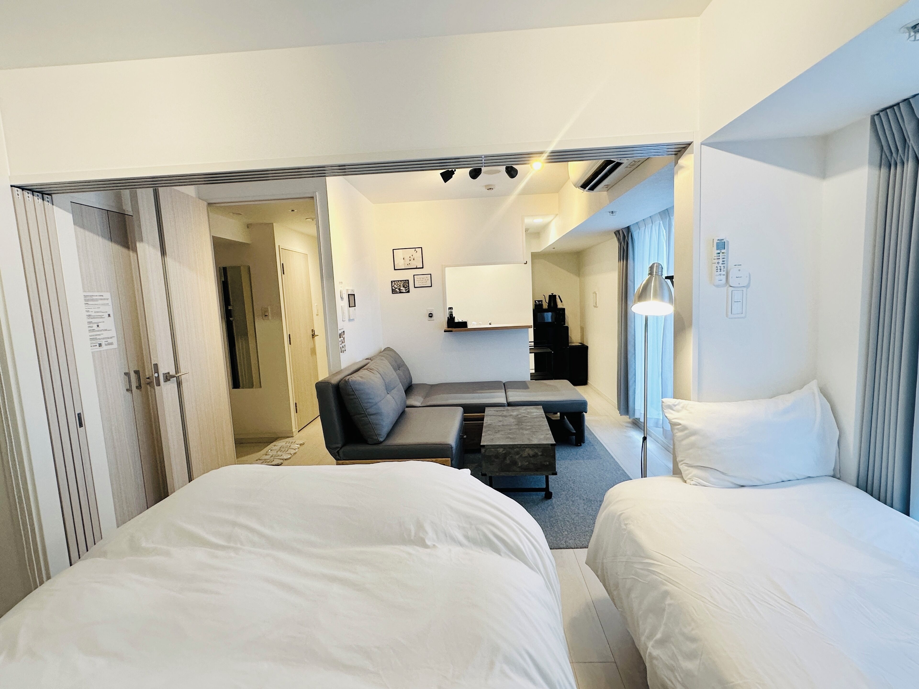 A hotel room with two beds, a sofa, a coffee table, and a desk with a computer.