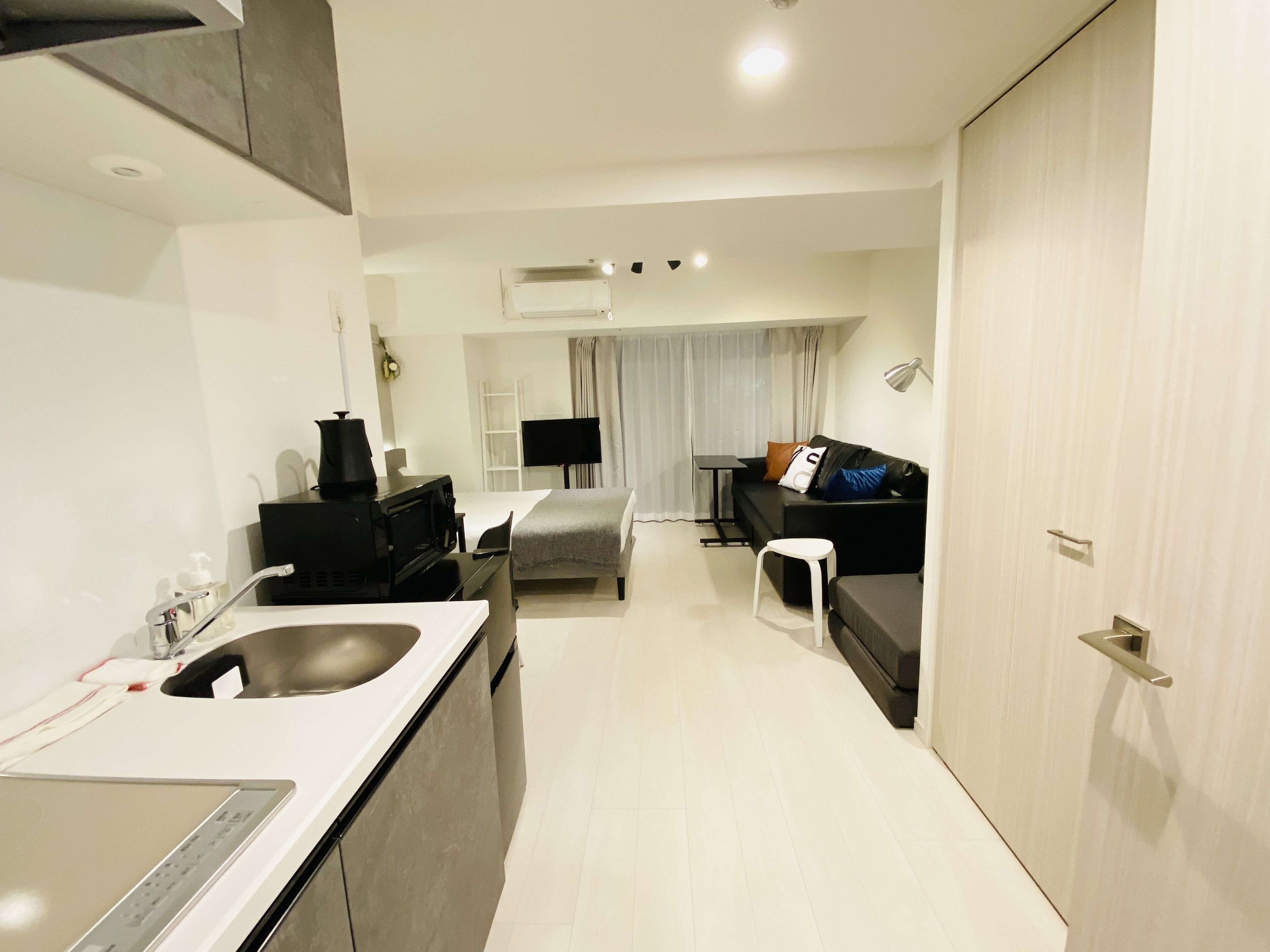 Een moderne hotelkamer met kitchenette, een bank, een kleine tafel en een televisie.