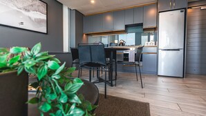 A modern kitchen with grey cabinets, a stainless steel refrigerator, and a dining area with black chairs and a table. - Umhlanga Arch Luxury Holiday or Work with Sea View (Durban)