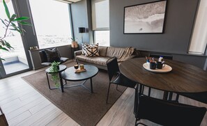 Een moderne woonkamer met een bank, twee bijzettafels en een eettafel.