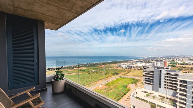 A balcony with a view of the sea and surrounding buildings. - Umhlanga Arch Luxury Holiday or Work with Sea View (Durban)