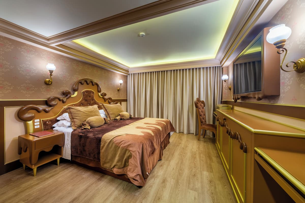 A well-appointed hotel room with a large bed, a nightstand, a dresser, and a television.