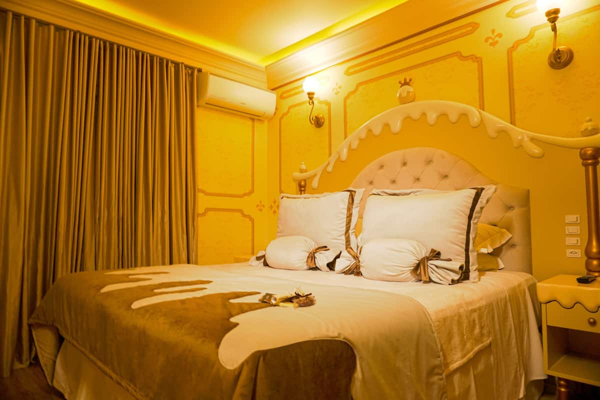 A hotel room with a large bed, a nightstand, and an air conditioning unit.