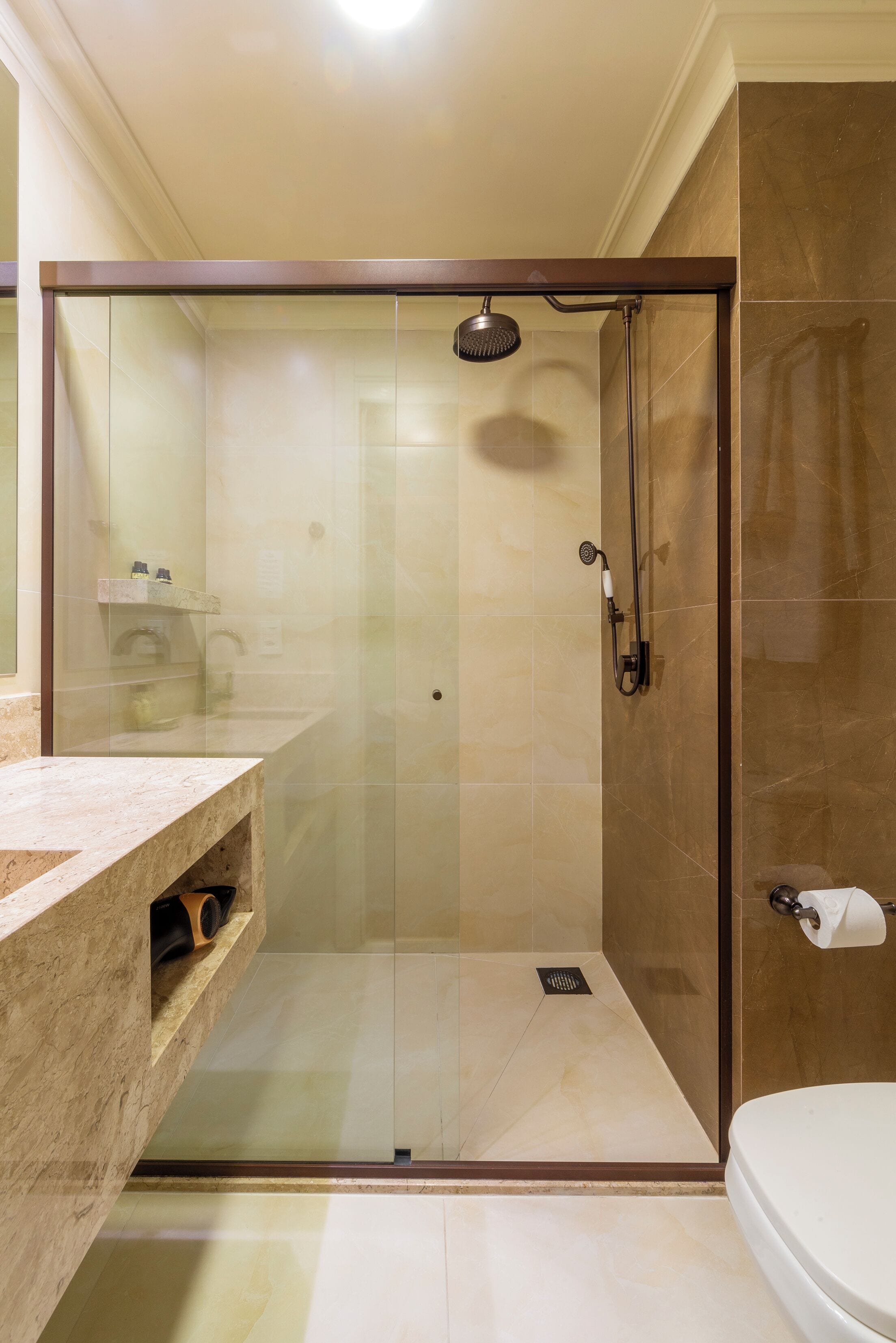 Un baño moderno con ducha de vidrio, encimera de mármol y un inodoro.