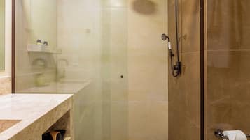 Un baño moderno con ducha de vidrio, encimera de mármol y un inodoro.