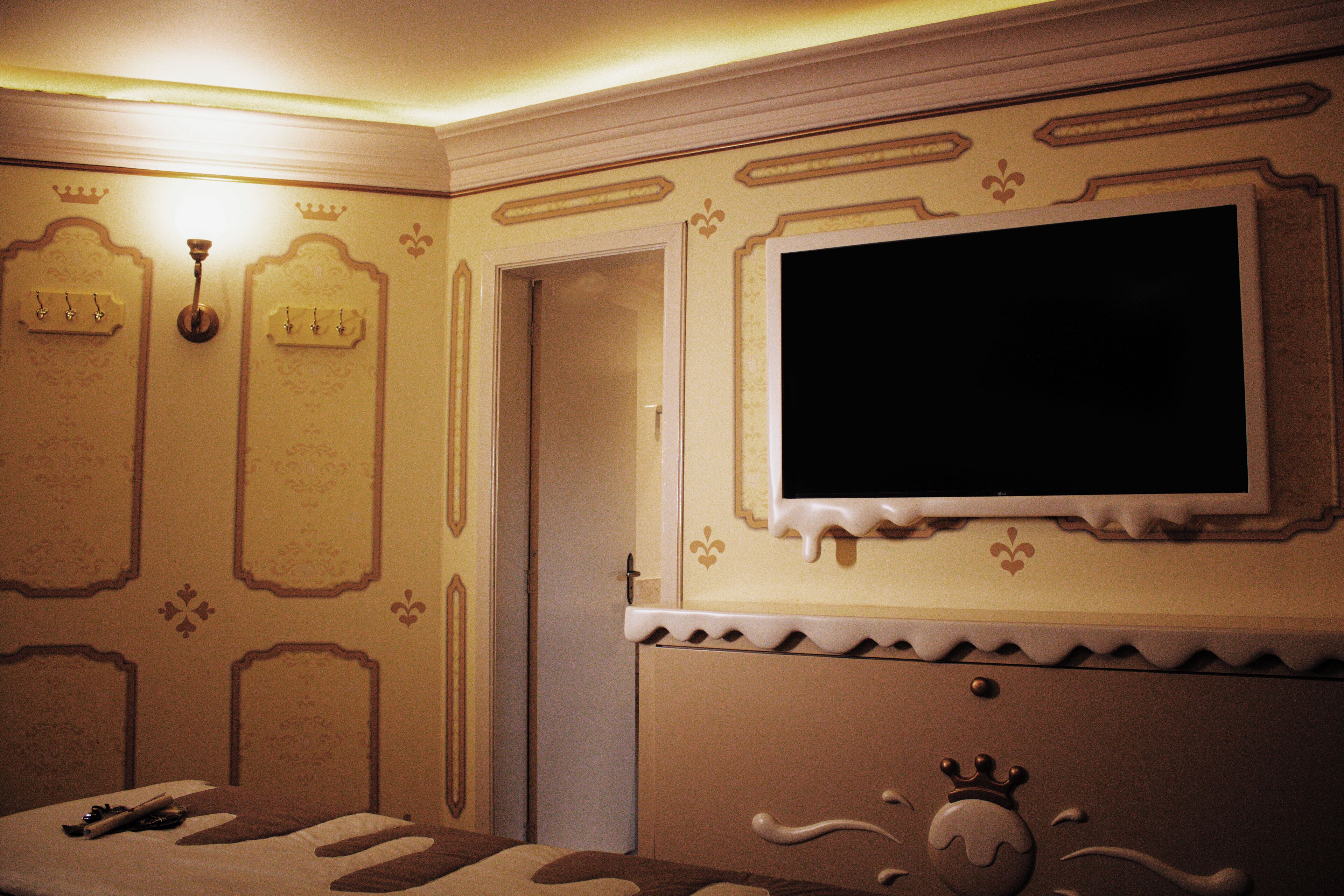 A hotel room with a bed, a television mounted on the wall, and a door.