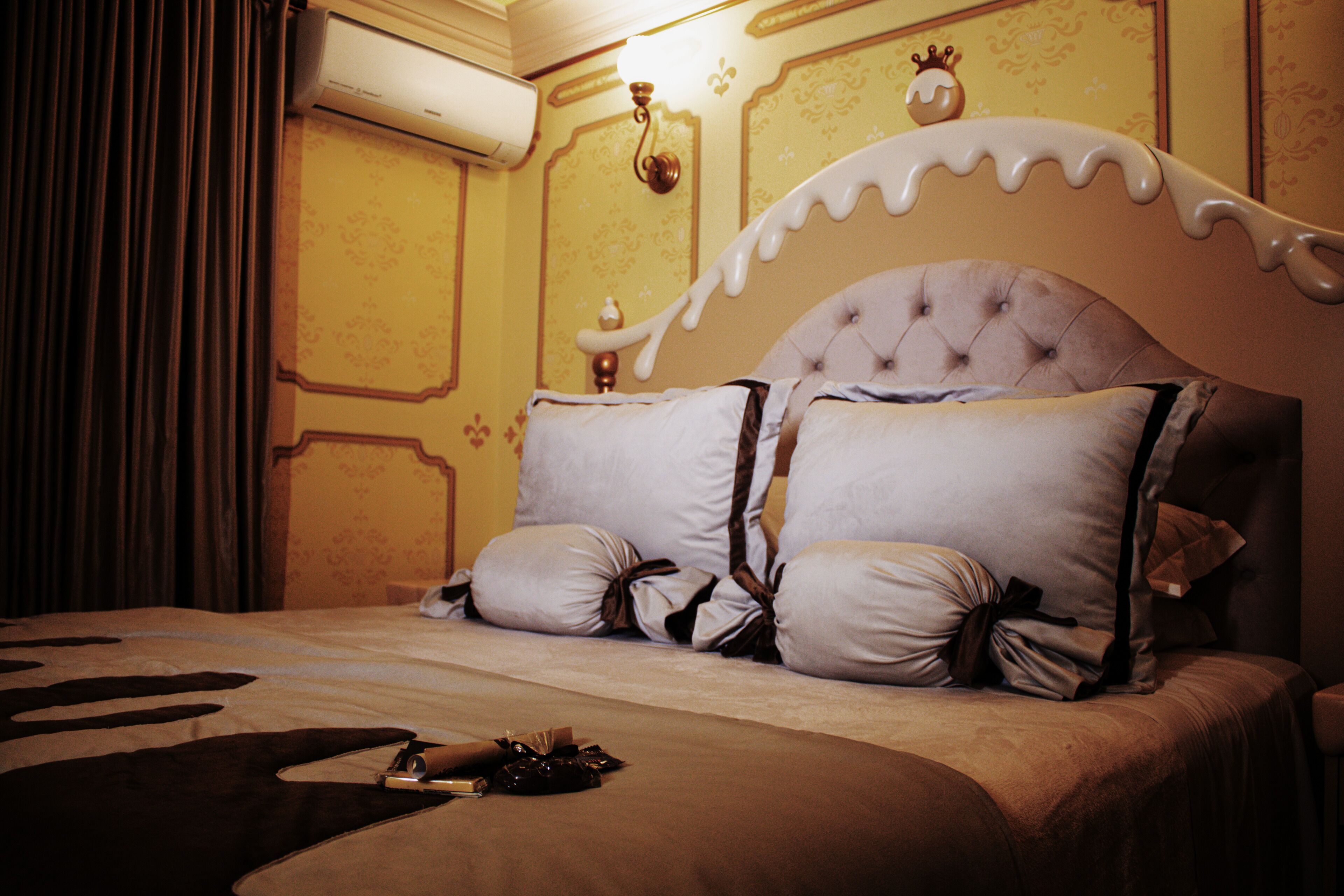 A bed with a white headboard, two large pillows, and a blanket.