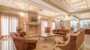 A spacious living room with a fireplace, plush seating, and a decorative ceiling. - Chocoland Hotel Gramado (Gramado)