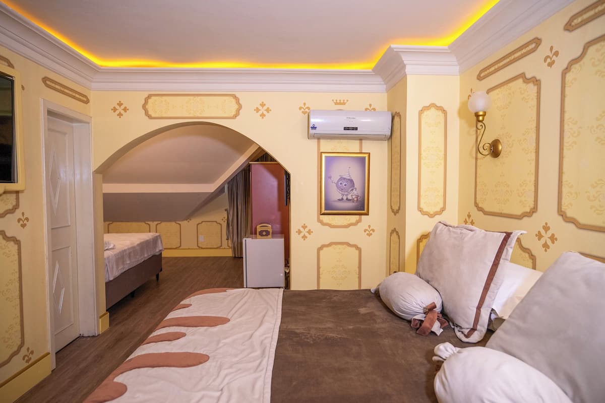 A hotel room with a bed, a desk, and an air conditioning unit.