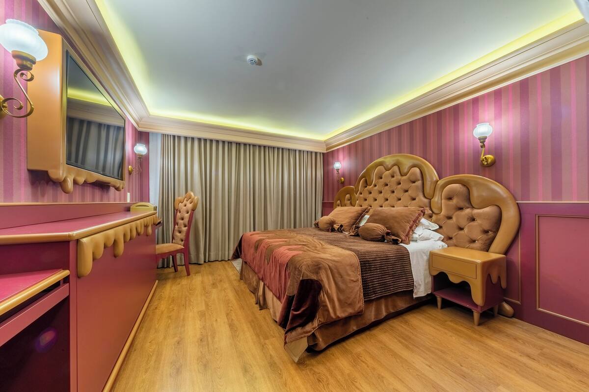 A bedroom with a large bed, a vanity with a mirror, and a chair.