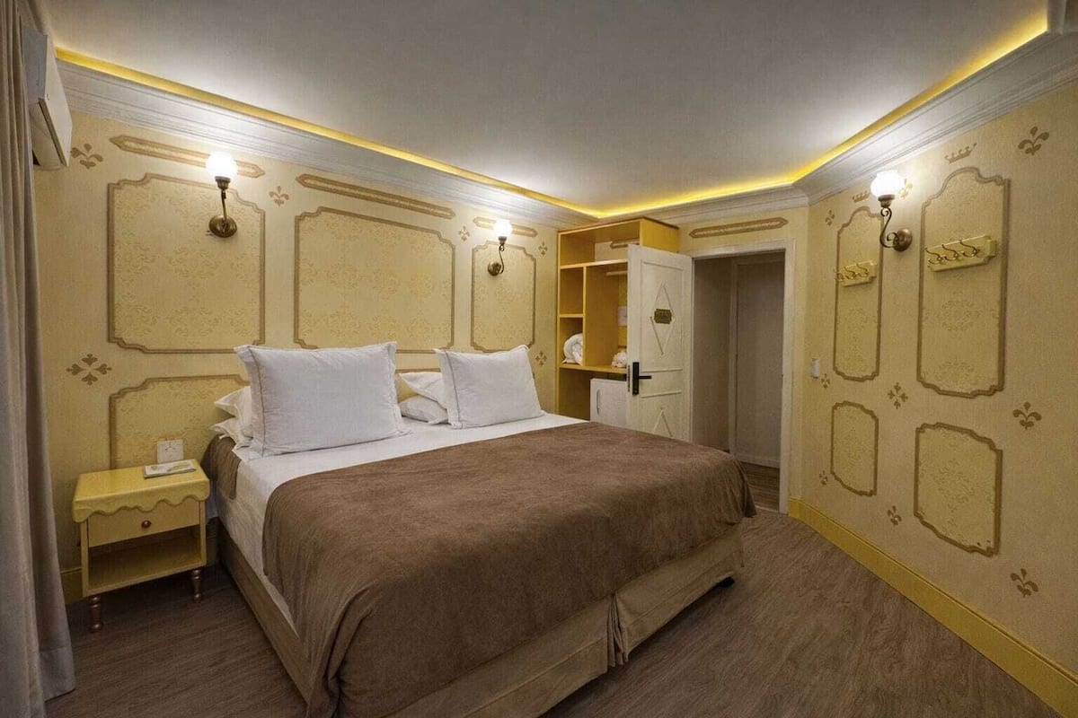 A hotel room with a large bed, bedside tables, and a wardrobe.