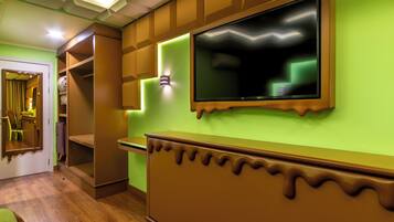 A room with a wooden cabinet, a television mounted on the wall, and a mirror on the door.