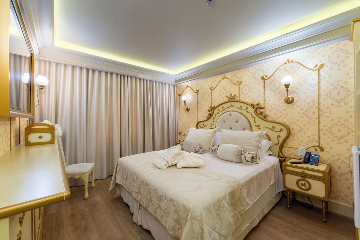 A hotel room with a large bed, bedside table, nightstand, and a chair.