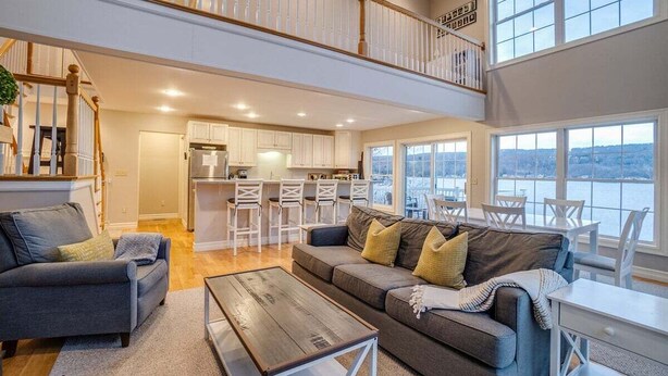 A spacious living area with a high ceiling, a staircase, and a kitchen area.