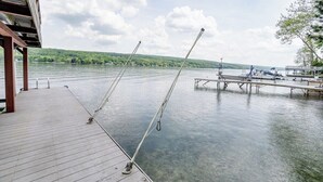 A wooden dock extending over calm water with fishing rods and a covered seating area.