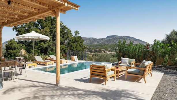 Un espace piscine avec des chaises longues, une pergola et une vue sur les montagnes.