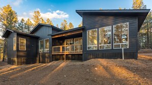 Ett modernt tvåvåningshus med stora fönster och en veranda.