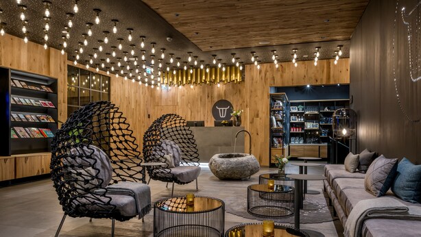 Un intérieur moderne avec un plafond en bois, des chaises en métal noir, un canapé et une table basse.