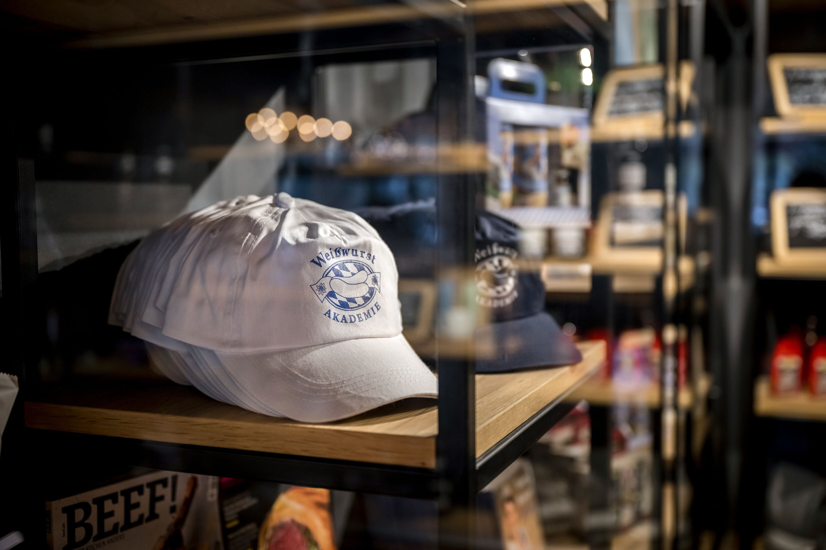 A display case with a white cap featuring a logo and text, and a magazine titled "BEEF!"