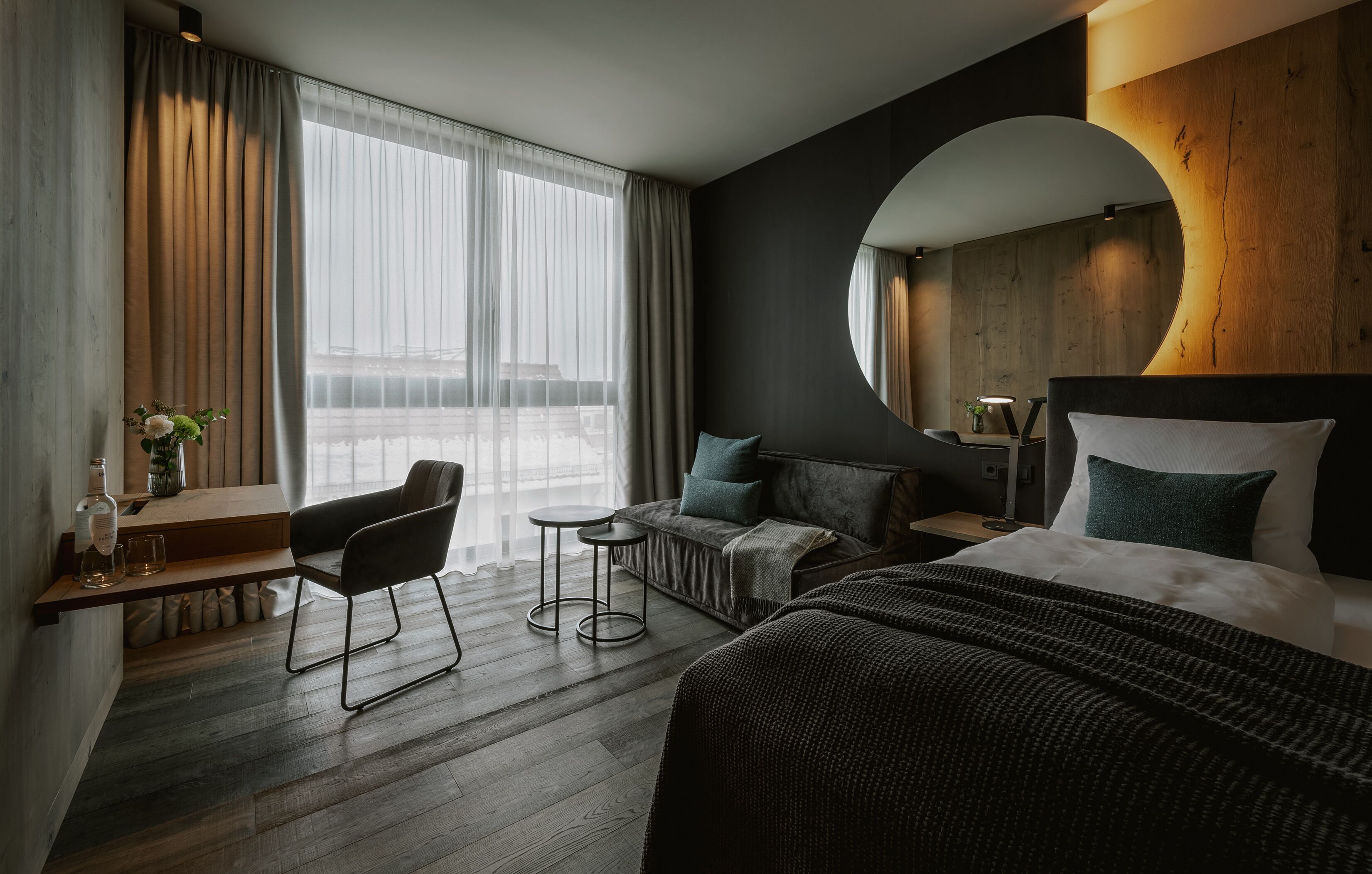 Une chambre d’hôtel moderne avec un grand lit, un canapé, un bureau avec une chaise et une petite table.