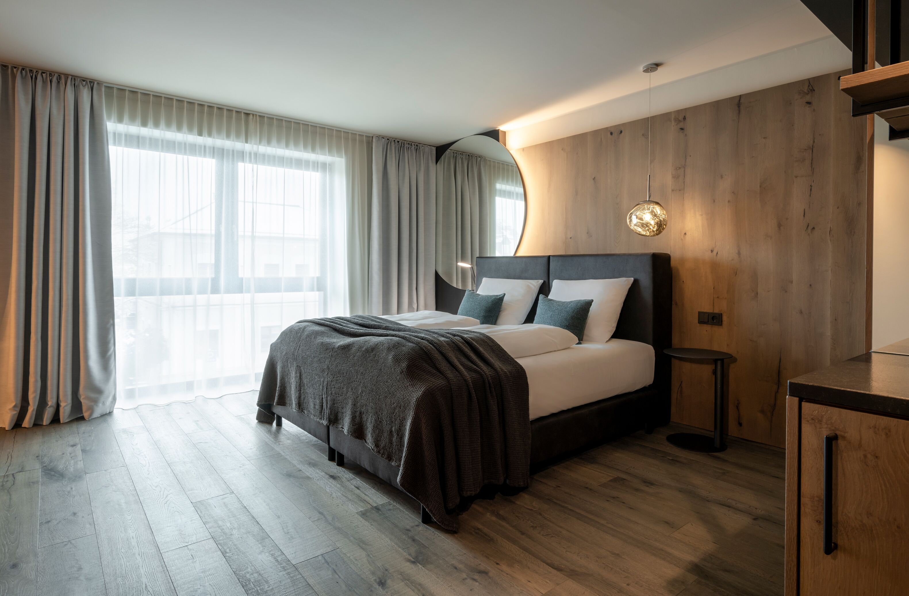 Un dormitorio moderno con una cama grande, suelo de madera y un panel de pared de madera.