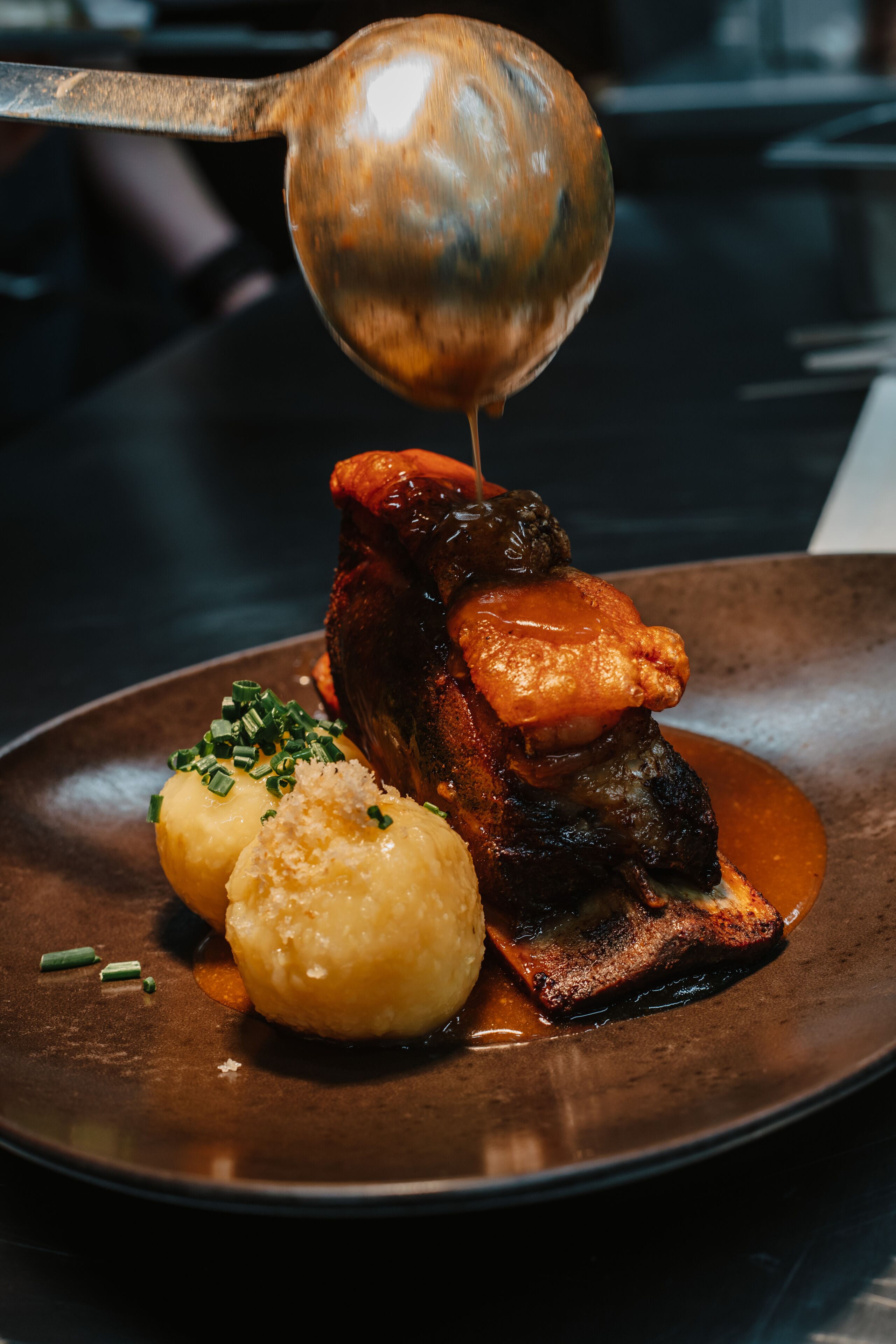 A plate of food with a spoonful of sauce being lifted.
