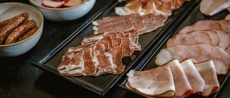 A variety of sliced meats on a tray, including ham and sausages.