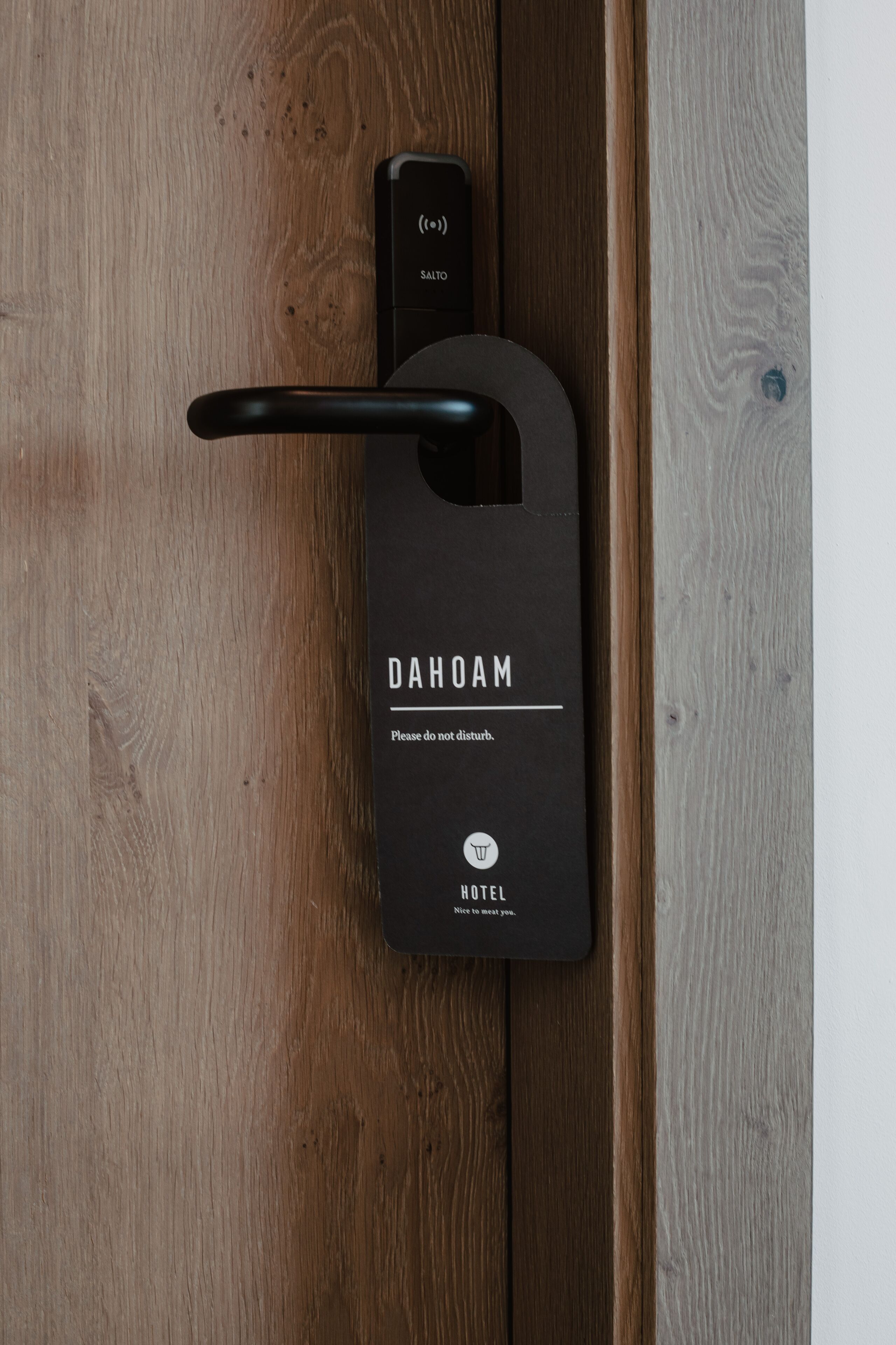 A black hotel door handle with the brand name "DAHOAM" and a note "Please do not disturb."