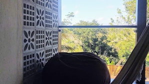 Una hamaca debajo de una estructura de madera con vista a la vegetación.