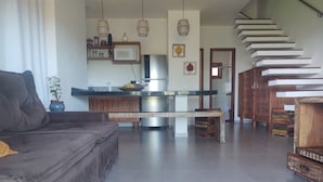 Una sala moderna con un sofá, una mesa de comedor y una zona de cocina con microondas y armarios.
