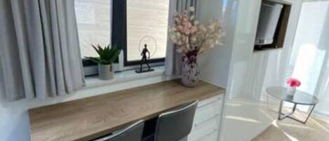 Un dormitorio moderno con una cama, un escritorio con dos sillas, una mesita y un televisor montado en la pared.