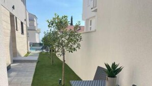 A narrow outdoor patio with a table and chairs, a small tree, and a potted plant. - Villa Laverna Annex (Novalja)