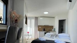 A modern hotel room with a bed, a desk, and a chair. There is a small kitchenette in the background. - Villa Laverna Annex (Novalja)