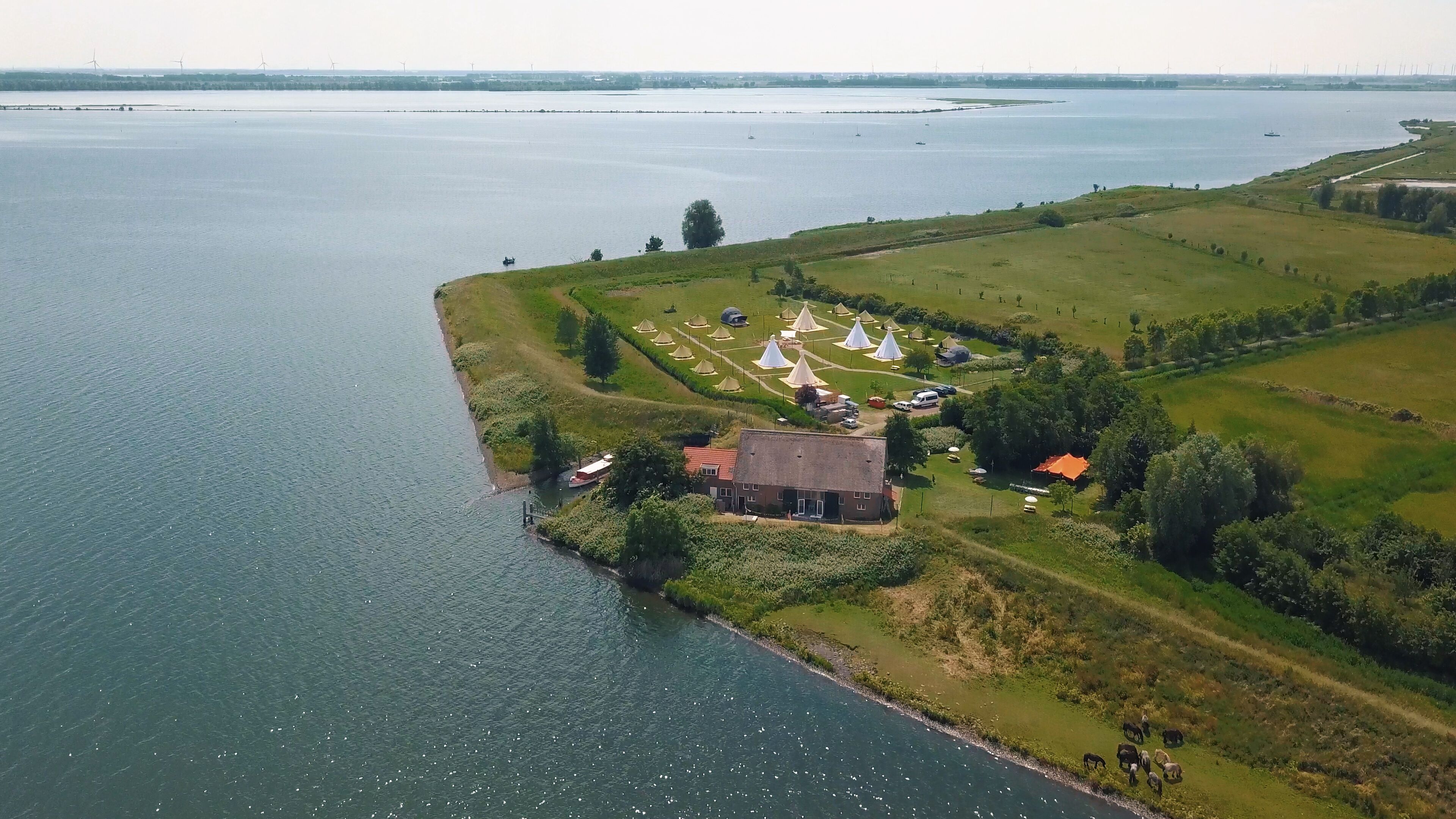 A lakeside property with a house, tents, and boats.