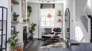 A modern living room with a fireplace, a black leather chair, and a staircase. - Stunning townhouse with large roof terrace (London)