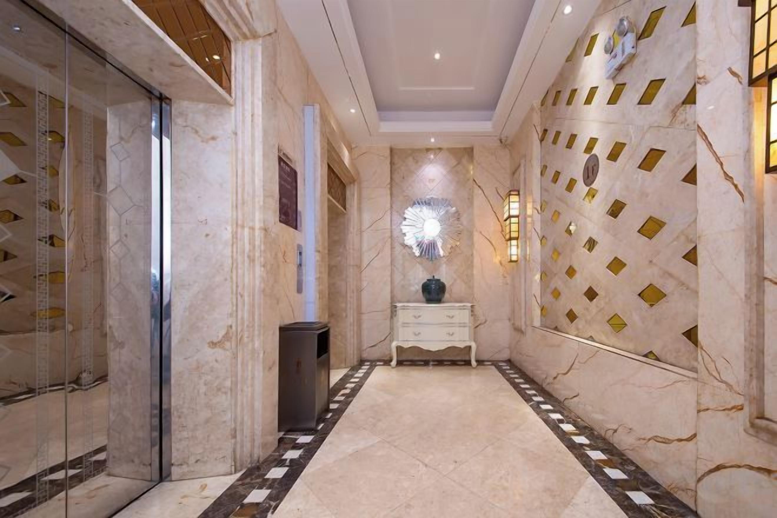 A hallway with marble flooring, a white console table, and a decorative wall with geometric patterns.