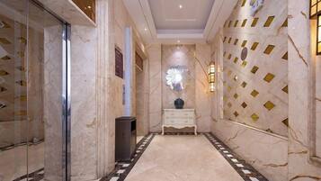 A hallway with marble flooring, a white console table, and a decorative wall with geometric patterns.
