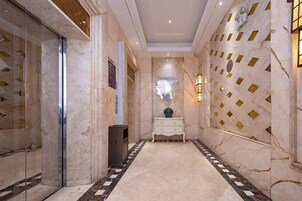 A hallway with marble flooring, a white console table, and a decorative wall with geometric patterns.