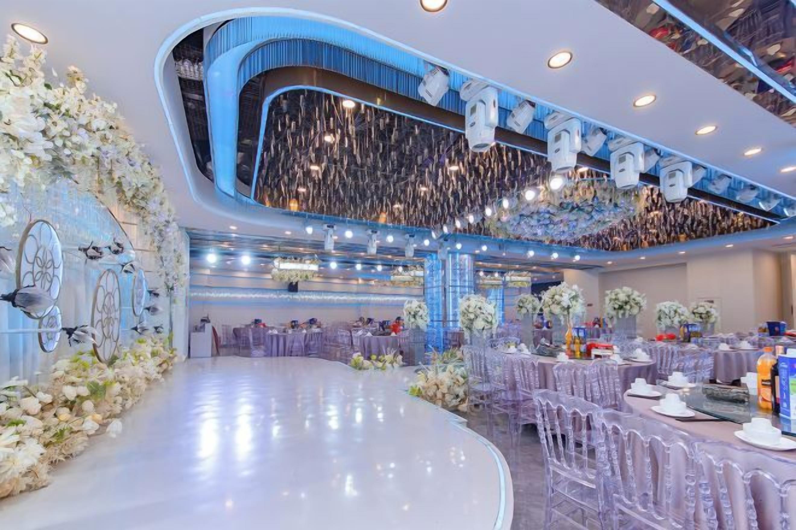 Un espacio interior amplio con asientos escalonados, arreglos florales decorativos y un diseño de techo moderno.