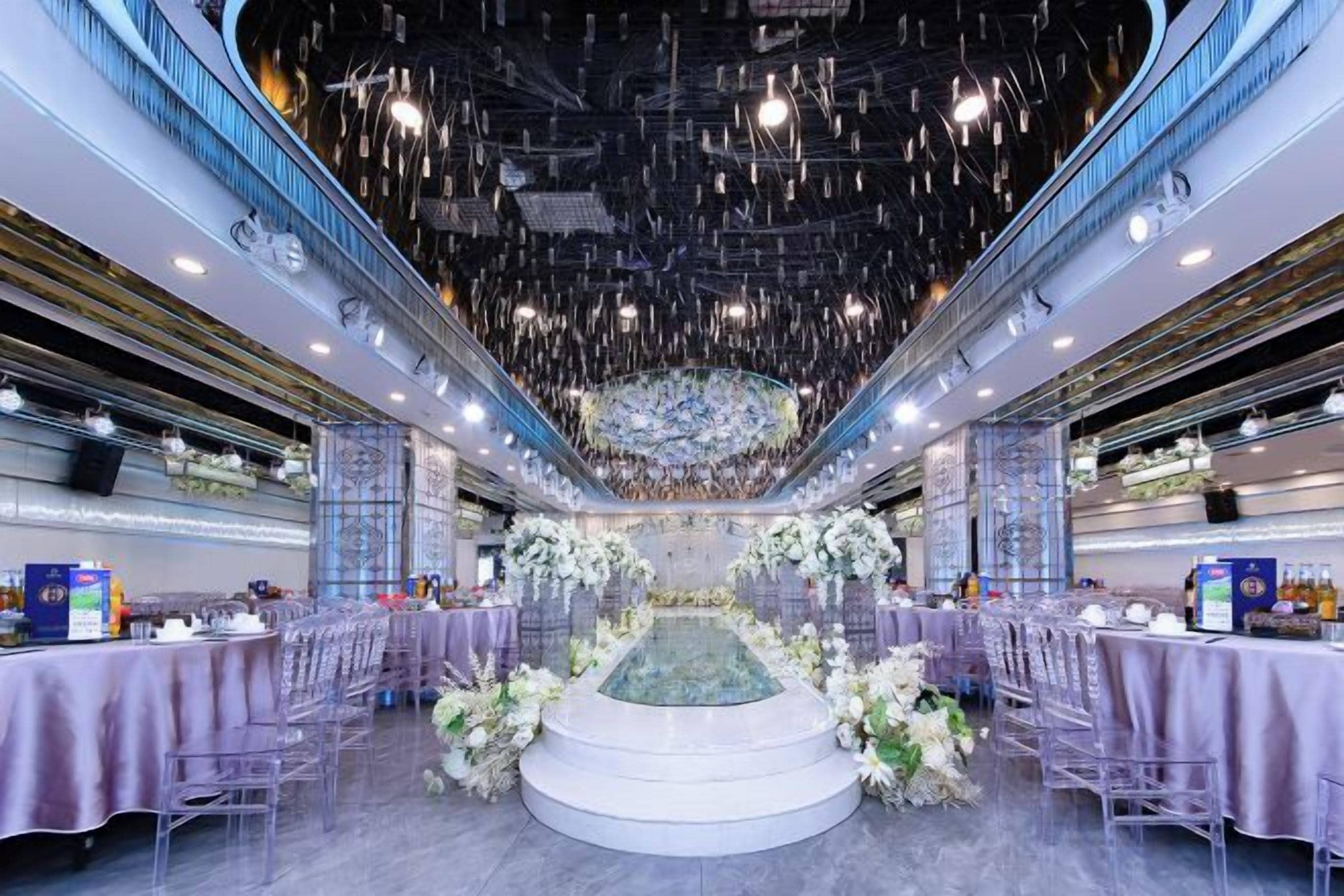 A spacious hall with tiered seating, a central stage, and a decorative fountain.
