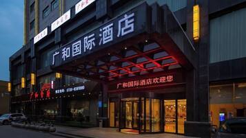 A hotel with a prominent entrance, signage, and a parking area.