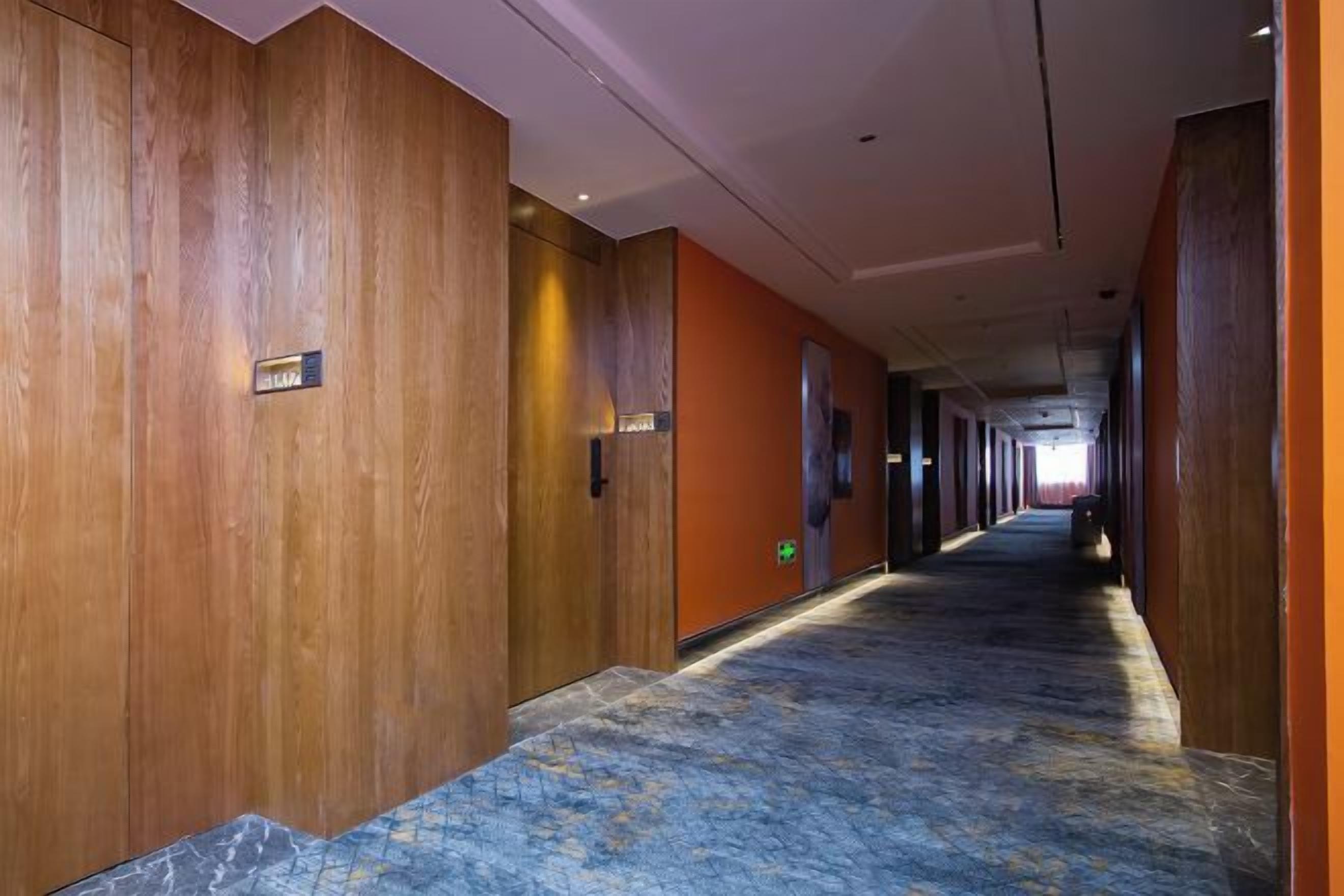 A long hallway with wooden paneling on the walls and a patterned carpet.