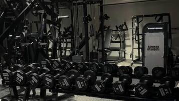 A gym with various weightlifting equipment and dumbbells.