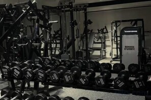 A gym with various weightlifting equipment and dumbbells. - Guanghe International Hotel (Yueyang)
