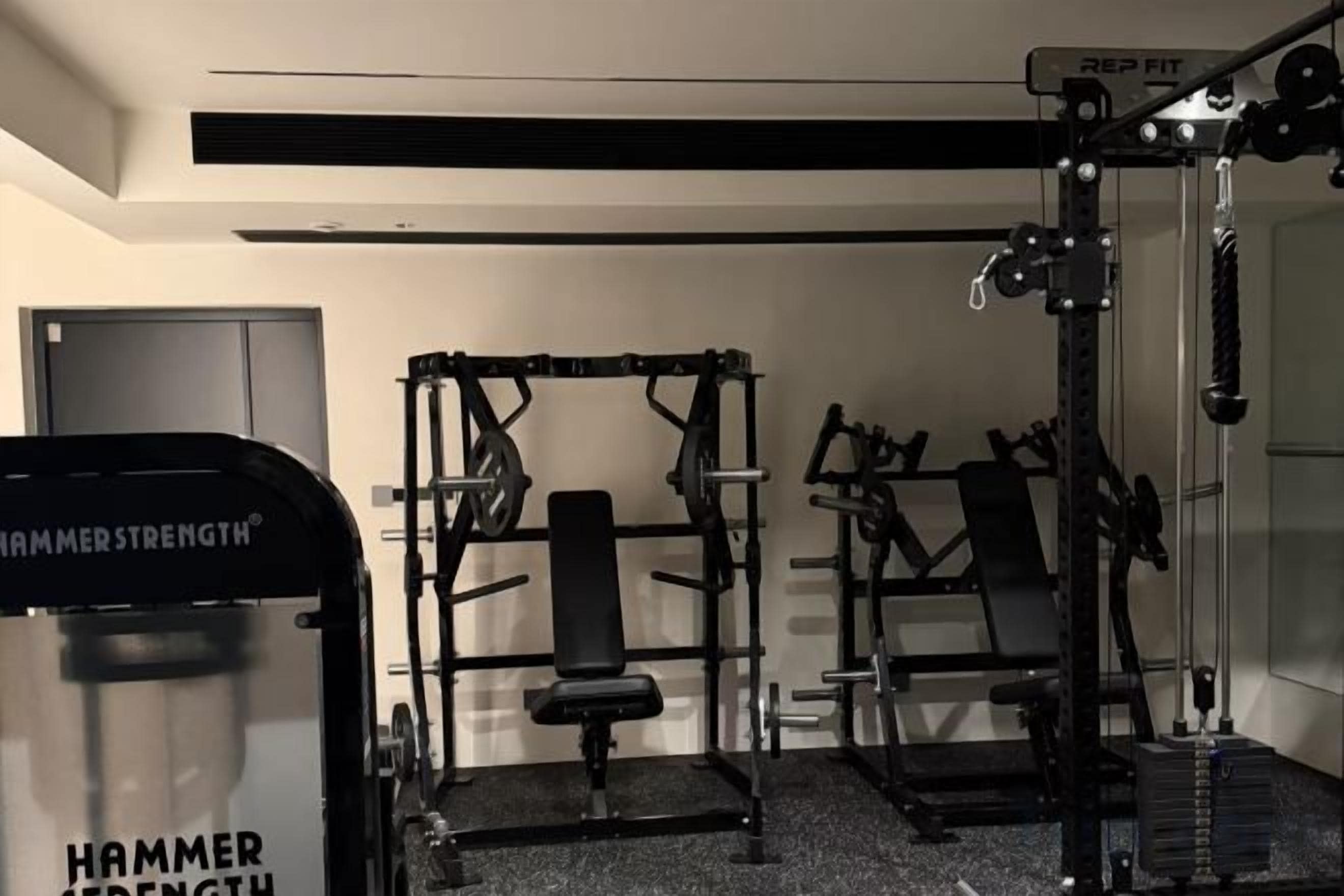 A home gym with a bench press, squat rack, and various weightlifting equipment.
