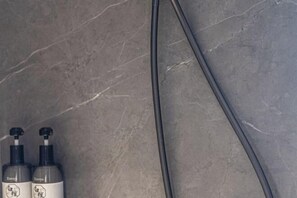 A bathroom with a marble wall, two bottles of hand soap, and a black cable. - Guanghe International Hotel (Yueyang)