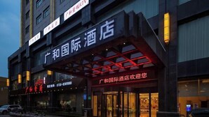 A hotel with a modern facade, featuring a prominent sign with Chinese characters.