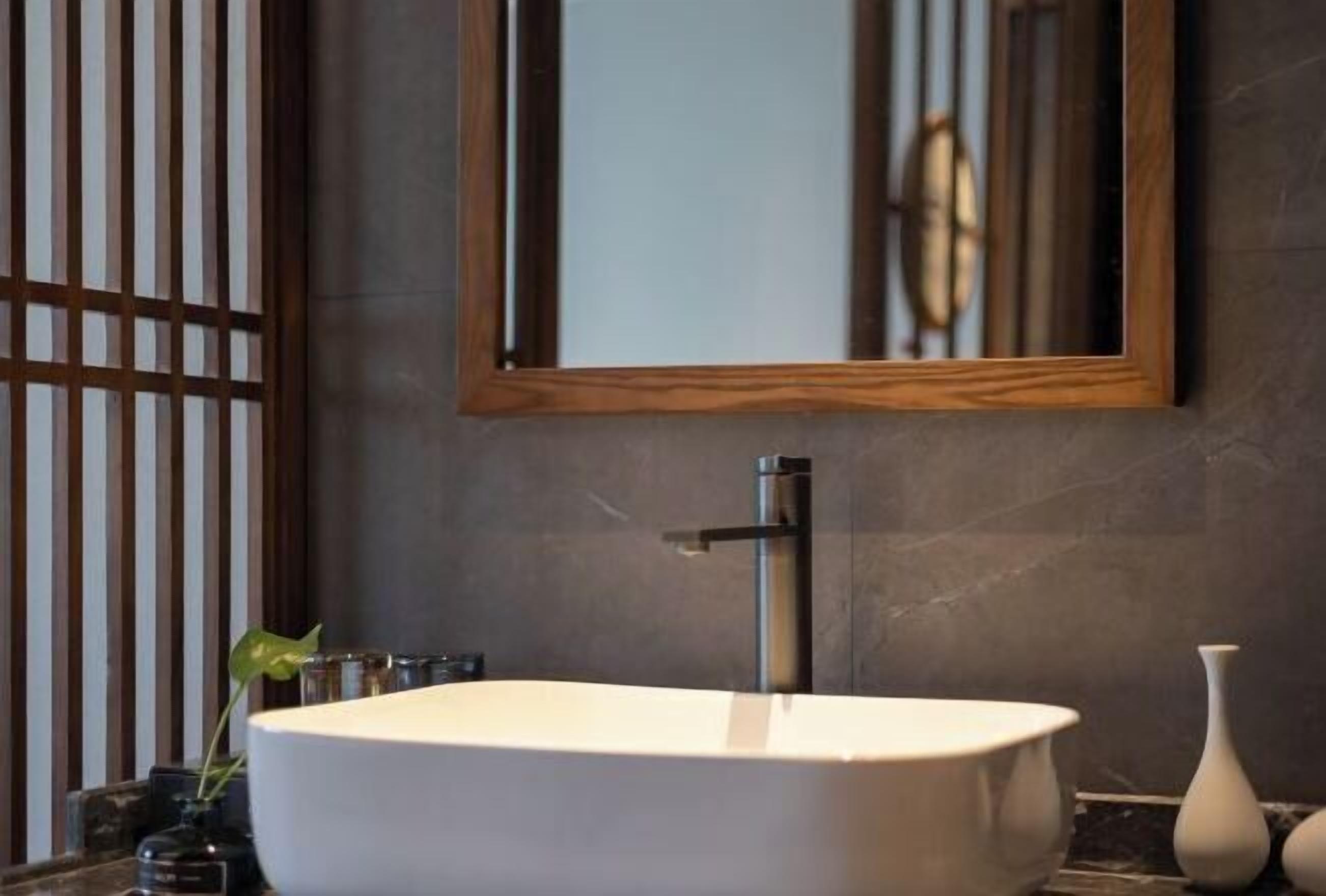 A modern bathroom with a large rectangular sink, a vertical faucet, and a mirror above it.