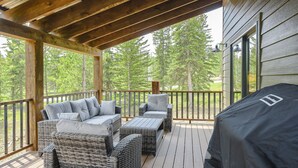 Une terrasse extérieure couverte, aménagée avec des meubles en osier et dotée d’un barbecue.